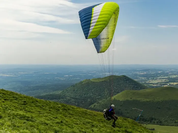 A paraglider above green hills