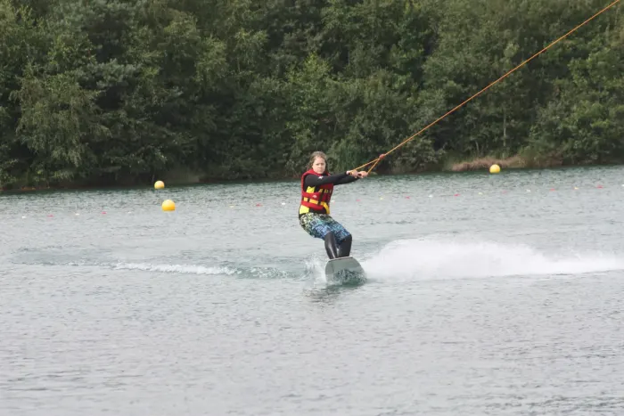 A wakeboarder pulled by an overhead cable across a lake, no boat in sight