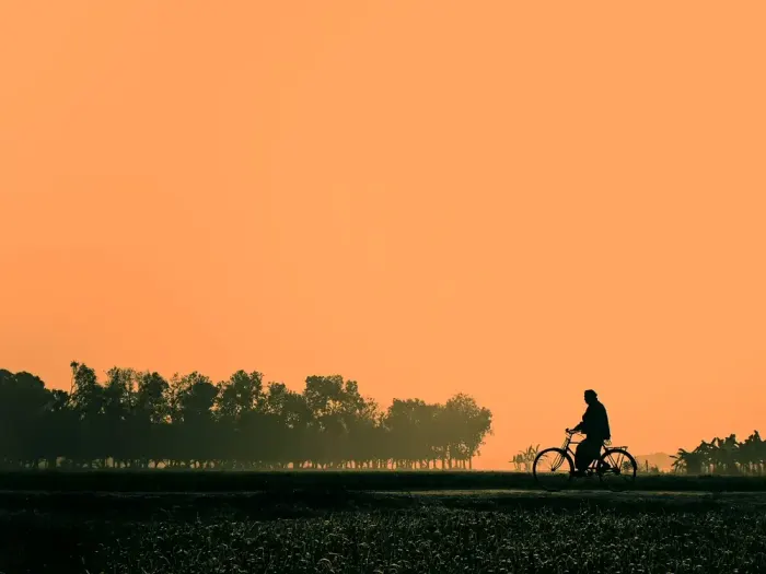 A cyclist in silhouette against an orange sky