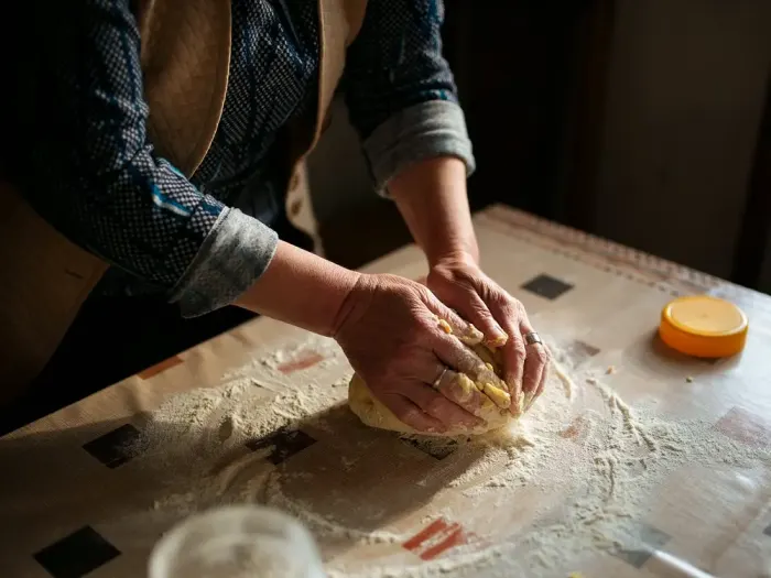 Hands kneading dough on a floured table