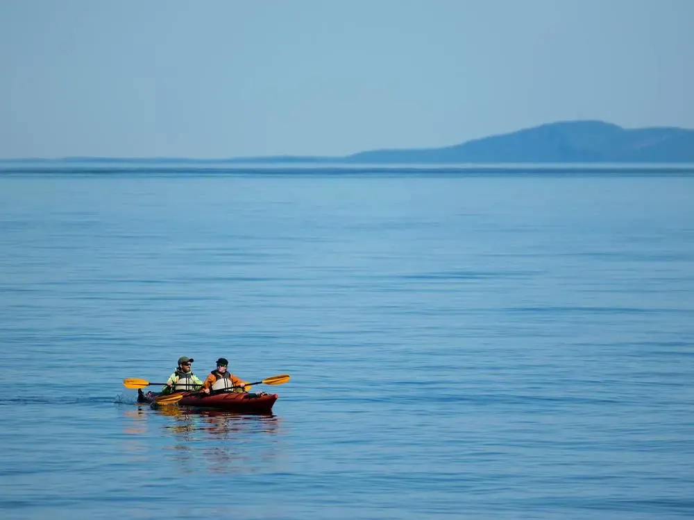 Two kayakers on a calm blue lake