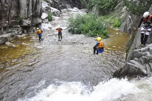 A canyoner in helmet and wetsuit in a river gorge