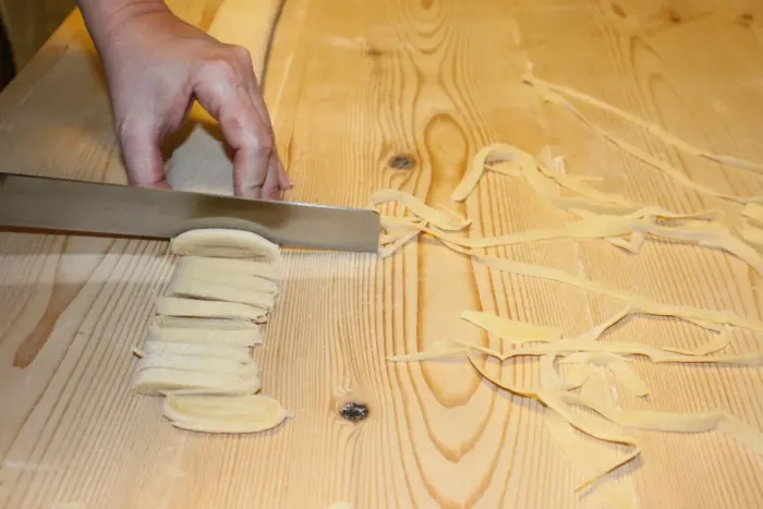 Fresh egg pasta being cut by hand with a knife