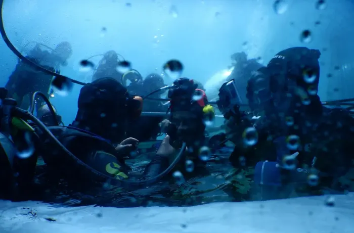 A scuba diver underwater in a wetsuit with tanks and mask