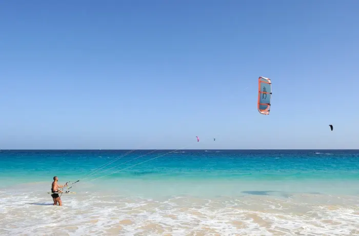 A kitesurfer riding across the water with a power kite overhead
