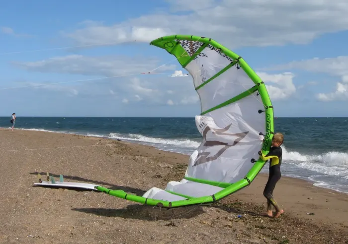 A kitesurfer riding across the water with a power kite overhead