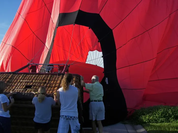 A hot air balloon being inflated, crew holding the basket