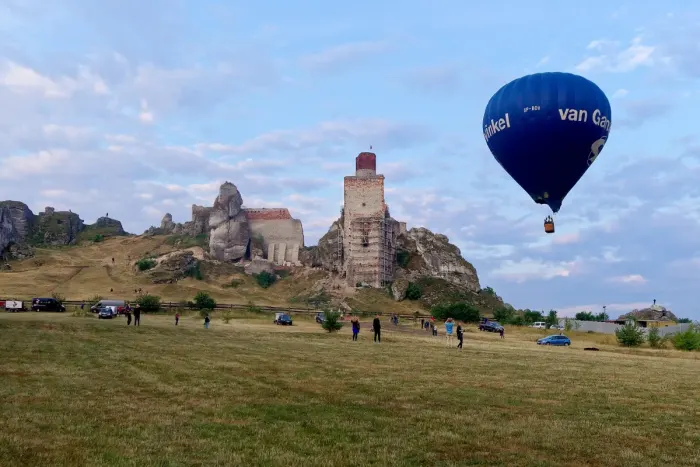A hot air balloon inflated and rising over open countryside