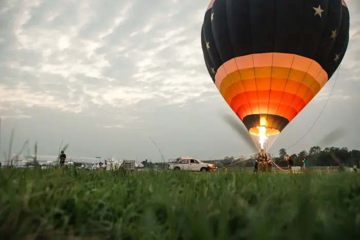 A hot air balloon inflated and rising over open countryside