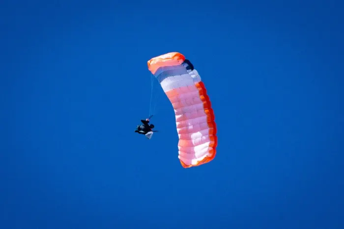 A skydiver under an open canopy against the sky