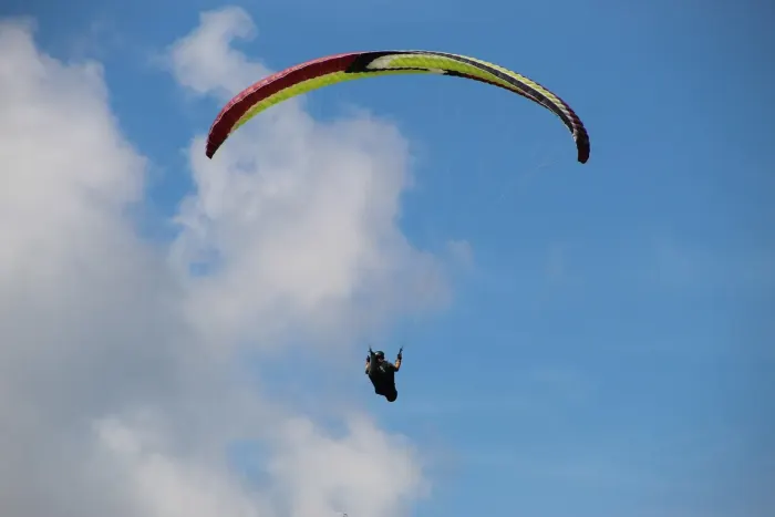 A tandem paraglider in flight above a lake