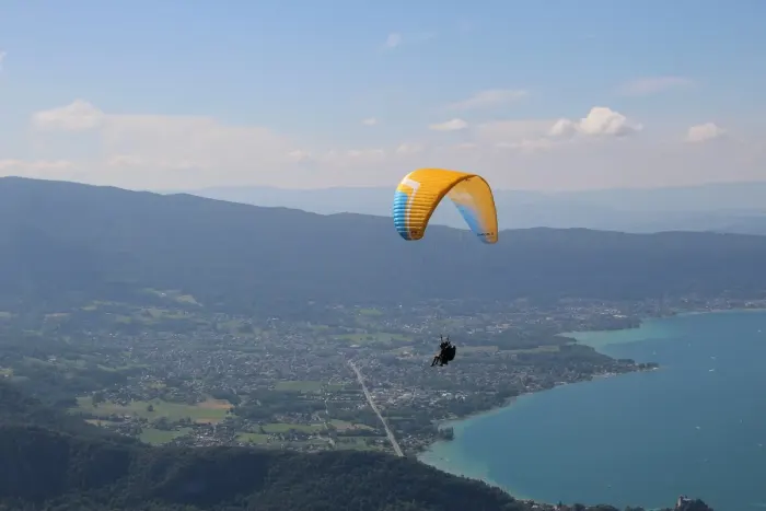 A paraglider above a lake, canopy open against the sky