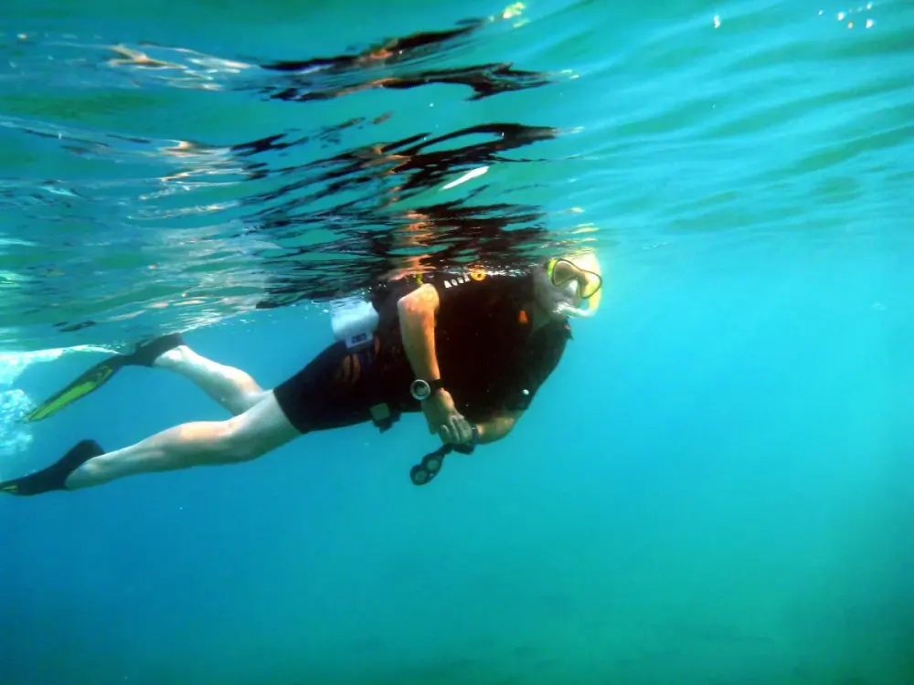A snorkeler floating face down in clear water