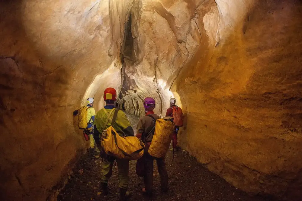 Cavers with kit bags in a lit cave passage