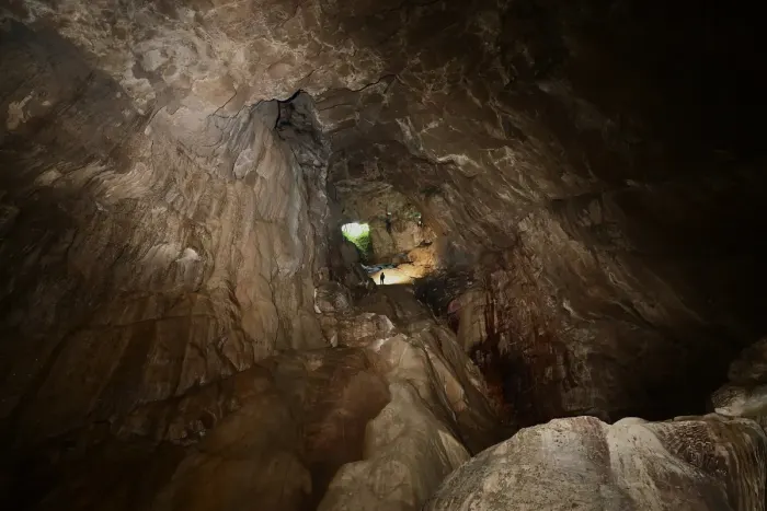 A caver with a headlamp inside a cave passage
