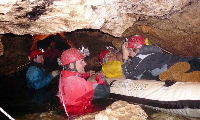 A caver with a headlamp inside a cave passage