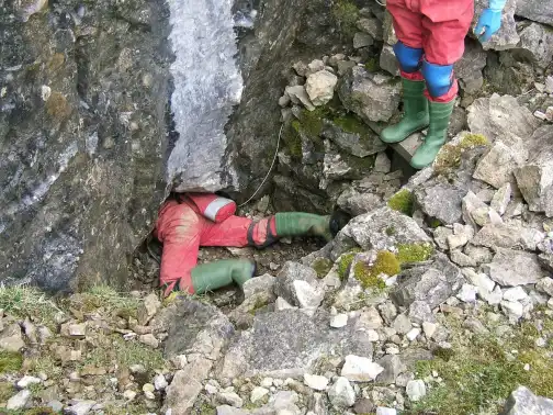 Cavers in helmets and overalls at a cave entrance