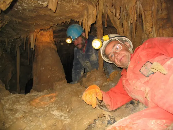 A caver with a headlamp inside a cave passage