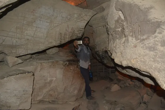 A caver with a headlamp inside a cave passage