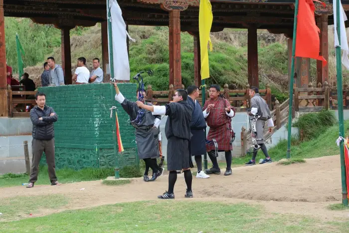 An archer drawing a bow on an outdoor shooting range