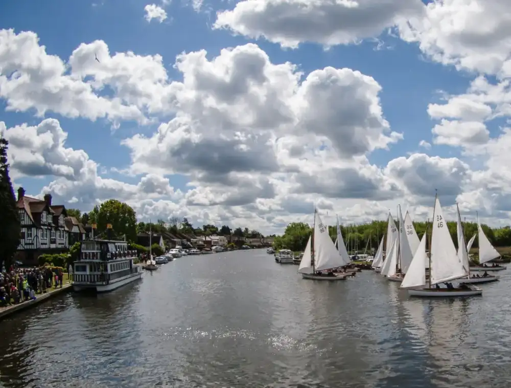 Sailing dinghies under white sails at the start of a race