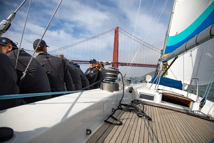 The deck of a sailing yacht under way, crew along the rail
