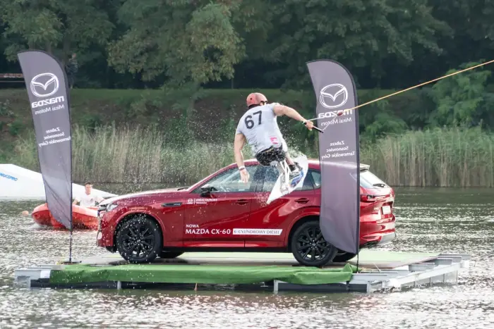 A wakeboarder skimming across flat water behind a towline