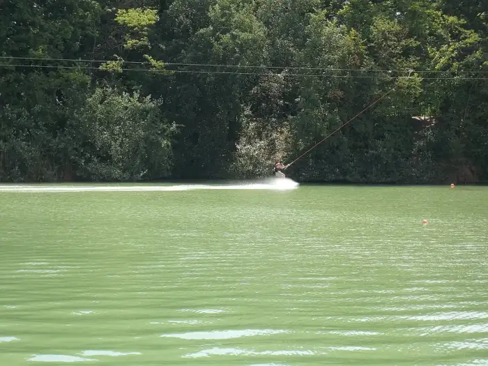 A wakeboarder skimming across flat water behind a towline