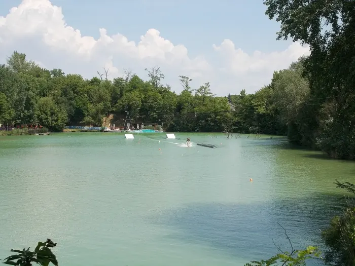 A wakeboarder skimming across flat water behind a towline