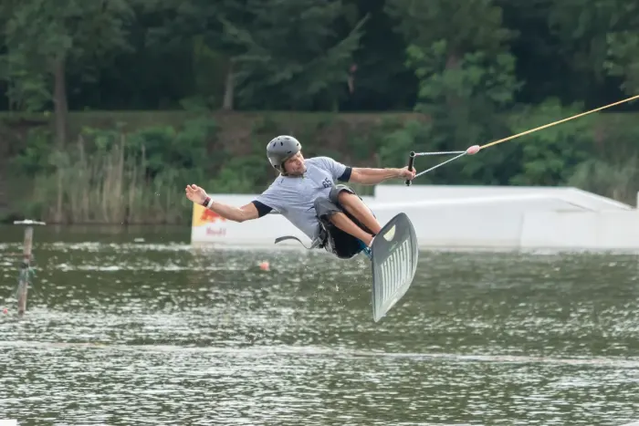 A wakeboarder skimming across flat water behind a towline