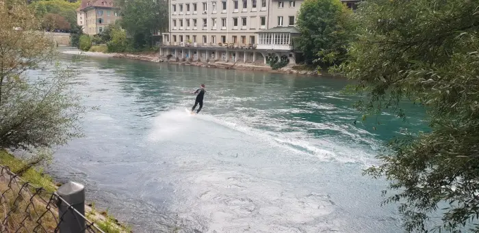 A wakeboarder skimming across flat water behind a towline