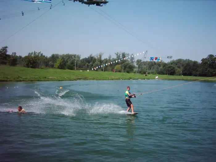 A wakeboarder skimming across flat water behind a towline