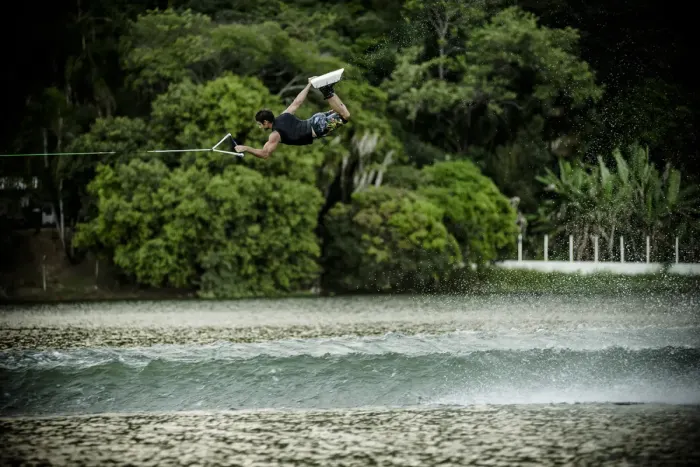 A wakeboarder skimming across flat water behind a towline